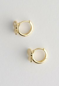 Kleine gouden creolen met vlinder-vormige bedels, elk met een kleine ingelegde heldere edelsteen.