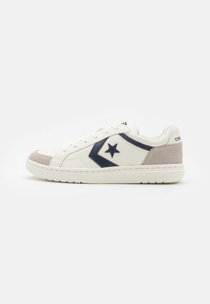 Weiße Ledersneaker mit navyblauen Akzenten, grauer Wildleder-Zehenkappe und Schnürung vorne. Verfügt über ein Stern-Logo und eine strukturierte Sohle.