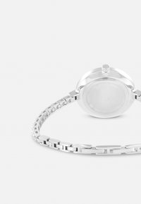 Reloj de acero inoxidable plateado con una caja redonda, corona texturizada y una pulsera eslabonada con eslabones rectangulares y cuadrados.