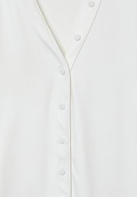 Weißes Hemd mit Knopfleiste, das ein V-Ausschnitt-Design, glatten Stoff und sechs passende Knöpfe entlang der Vorderkante aufweist.