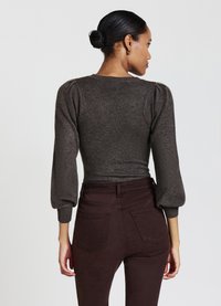 Maglione a maglia grigio scuro con maniche a sbuffo e design adatto, abbinato a jeans a vita alta color bordeaux scuro. Texture liscia e stile contemporaneo.