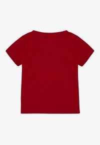 Crvena majica kratkih rukava od pamuka. Ima zaobljeni izrez i jednobojni dizajn bez uzoraka ili detalja. Čist i jednostavan dizajn.