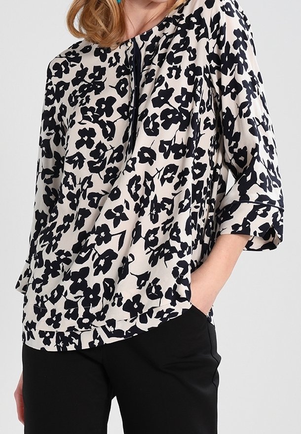 Blouse à motif floral en crème et marine, avec une coupe ample, des manches trois-quarts et un col rond orné d'un détail de pli subtil.