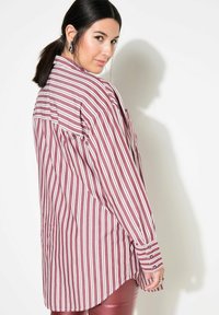 Langarmshirt in bordeaux met witte verticale strepen, voorzien van een knoopmanchet en een ronde zoom. Glad stoffen met een comfortabele pasvorm.