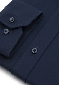 Granatowa koszula wizytowa z długimi rękawami, z kołnierzykiem typu wskazującego, z dwoma guzikami na każdym mankiecie oraz teksturowanym materiałem. Czarne guziki z detalami logo.