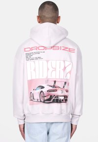 Helle rosa Kapuzenjacke mit einem großen Grafikdruck auf dem Rücken eines Sportwagens, einschließlich fett gedrucktem Text und Renndetails. Weicher Stoff, lässige Passform.