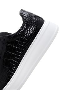 Zapatillas de cuero negro con estampado de cocodrilo y suela de goma blanca, que cuentan con una puntera redondeada y un diseño elegante para un aspecto moderno.