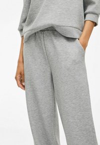 Graue Sweatpants aus strukturiertem Stoff, mit lockerer Passform, elastischem Bund und Seitentaschen. Teil eines lässigen Outfits.