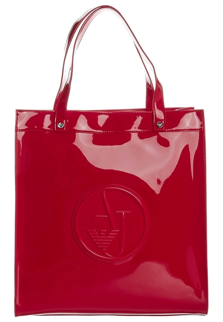 Röd, blank PVC-väskan med två handtag, med en cirkulär präglad logotyp i mitten. Mjuk textur och slank design.