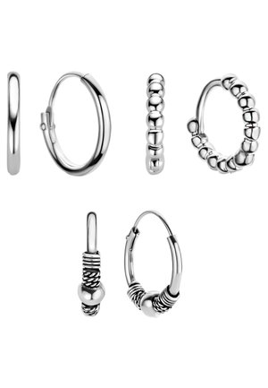 Cinq paires de boucles d'oreilles créoles argentées avec des designs lisses, perlés et en fil enroulé, présentées de face et de côté sur un fond blanc.