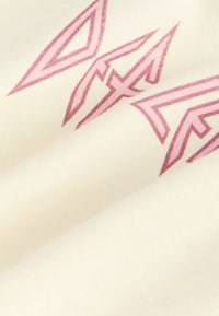 Baumwollstoff in Cremefarbe mit eckigen, rosa geometrischen Mustern. Die Textur wirkt glatt mit leichtem Glanz.