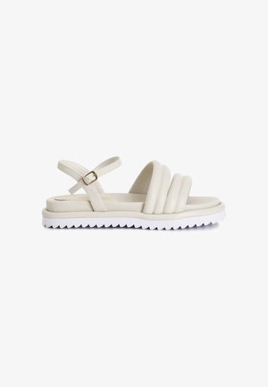 Beige Plattform-Sandalen mit drei dicken, runden Riemen und einer Schnallenverstellung. Die Sohle ist weiß mit einem gezackten Rand für besseren Halt.