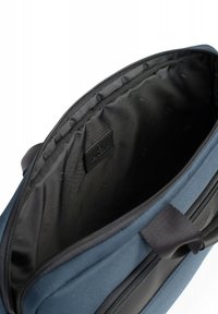 Blauwe stoffen tas met een zwarte binnenkant, voorzien van een ritssluiting en een klein, ontspannen logo-etiket op de voering. Geverfde buitenkant.