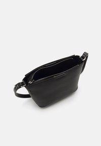 Sort lædertaske med lynlås, der har en glat overflade og et minimalistisk design. Inkluderer en skulderrem for nem transport.