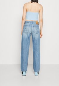 Ljusblåa korta toppar i kombination med vida ljusblå denimjeans. Jeansen har bakfickor och en märkesläderlapp vid midjan.