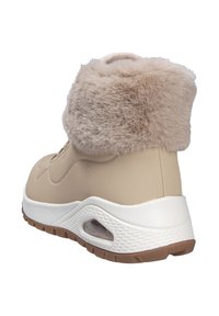 Bota de invierno beige con puño de pelo sintético, suela de goma y detalles texturizados. El diseño incluye un collar acolchado y un orificio de ventilación.