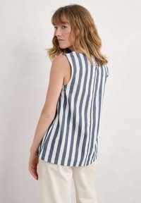 Beżowy top bez rękawów w paski w niebiesko-białym kolorze, o prostym kroju z okrągłym dekoltem i miękkim, lekkim materiale.