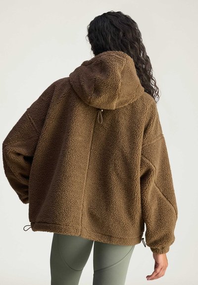 Brown fleece jacket with a hood, featuring a textured surface and drawstring details at the hem and cuffs. Loose-fitting design.