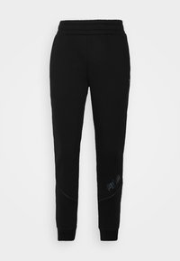 Pantalones de chándal negros hechos de una tela suave, con pierna ajustada, cinturilla elástica y un pequeño logo impreso cerca del dobladillo.