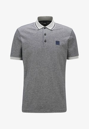 Polo gris avec un tissu texturé, trois boutons noirs, un col et des manches rayés blancs, et un patch logo bleu marine sur la poitrine.