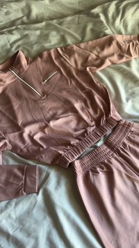 Różowy dres składający się z bluzy z ćwierć-zapięciem i kieszenią na piersi oraz pasujących spodni z elastycznym pasem i ściągaczami na mankietach.