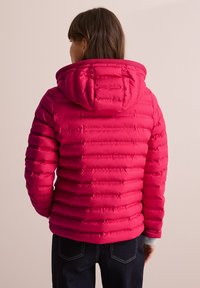 Giacca imbottita rosa con cappuccio, caratterizzata da un design trapuntato e strisce orizzontali. Il materiale sembra liscio con una leggera lucentezza.