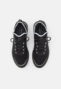 Chaussures de sport noires avec une tige en mesh texturé, des accents gris, un bout arrondi et des lacets plats. Elles disposent d'une semelle intérieure rembourrée et d'une semelle flexible.