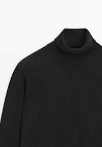 Maglione dolcevita nero realizzato in un tessuto a maglia liscia. Vestibilità classica con colletto e polsini a costine, caratterizzato da un design con maniche continue.