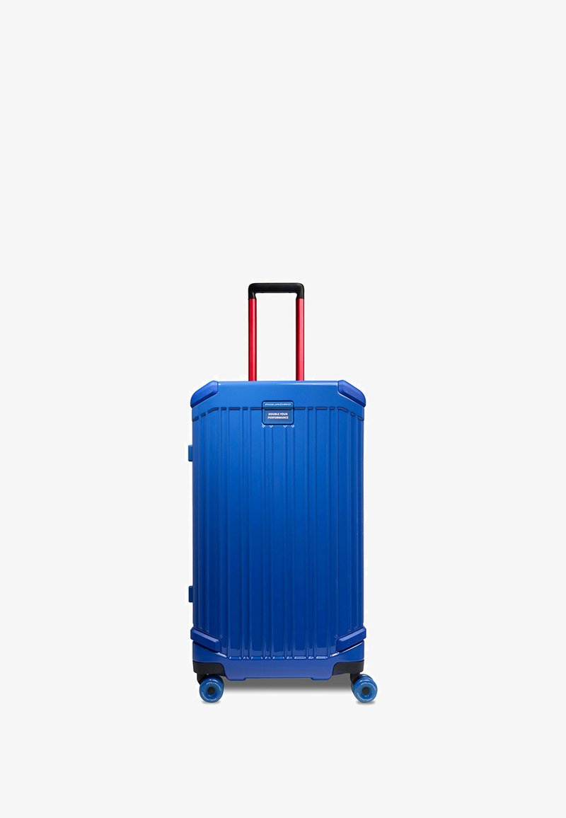 Hartschalenkoffer in Blau mit vertikalen Rillen, ausziehbarem schwarzem Griff und roten Akzenten. Vier blaue Räder für einfache Mobilität.