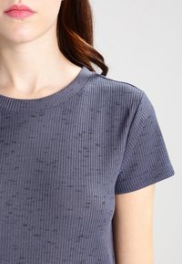 Ribbade, mörkgrå t-shirt med korta ärmar och rund halsringning, med ett strukturerat mönster över hela tyget.