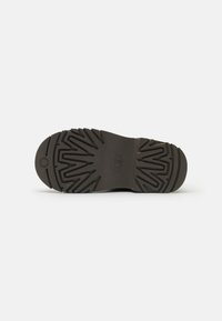 Suela de goma negra con un patrón de relieve profundo. Punta redondeada y superficie texturizada, con logotipo de la marca en relieve. Bordes reforzados para mayor durabilidad.