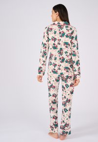 Completo pigiama floreale con maniche lunghe e pantaloni, caratterizzato da una base crema e motivi floreali multicolori. Tessuto morbido con una vestibilità comoda.