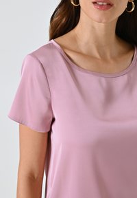Helles rosa Satin-Oberteil mit kurzen Ärmeln, weitem Rundhalsausschnitt und glatter Textur. Einfaches Design ohne sichtbare Muster oder Beschläge.