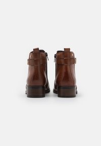 Hnědé kotníkové boty z hladké kůže, se zipy na boku a zlatými kovovými doplňky. Design s podpatkem ve vrstveném stylu pro stabilitu.