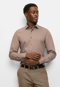 Light brown button-up shirt with a spread collar, slim fit, long sleeves, and dark buttons, paired with beige trousers and a brown belt.