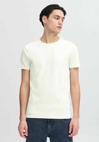 Tricou scurt cu maneci scurte, de culoare bej deschis, realizat din bumbac moale, având un guler rotund și o croială slim. Purtați-l cu blugi negri.