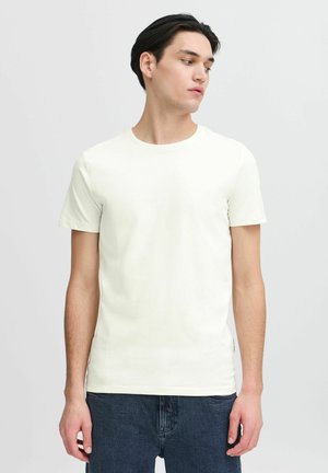 Light beige short-sleeve t-shirt made of soft cotton, featuring a round neckline and a slim fit. Worn with dark jeans.