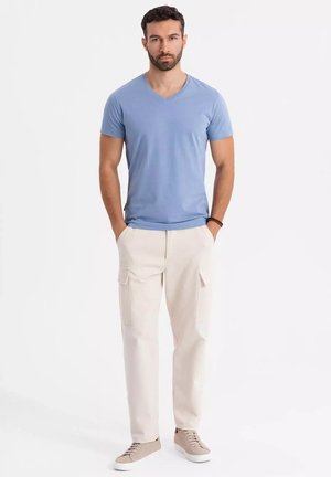 Lyseblå v-hals t-shirt parret med beige cargo-bukser med sidelommer, afsluttet med lysebrune snøresneakers.