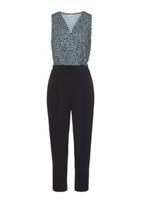 Mouwloze jumpsuit met een lichtgroene top met zwarte vlekken en een V-hals, gecombineerd met zwarte tapered trousers en een gladde tailleband.