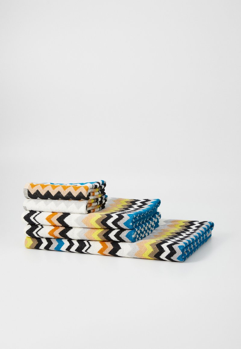 Set of patterned towels featuring zigzag designs in black, white, blue, orange, and yellow. Soft texture, various sizes stacked.