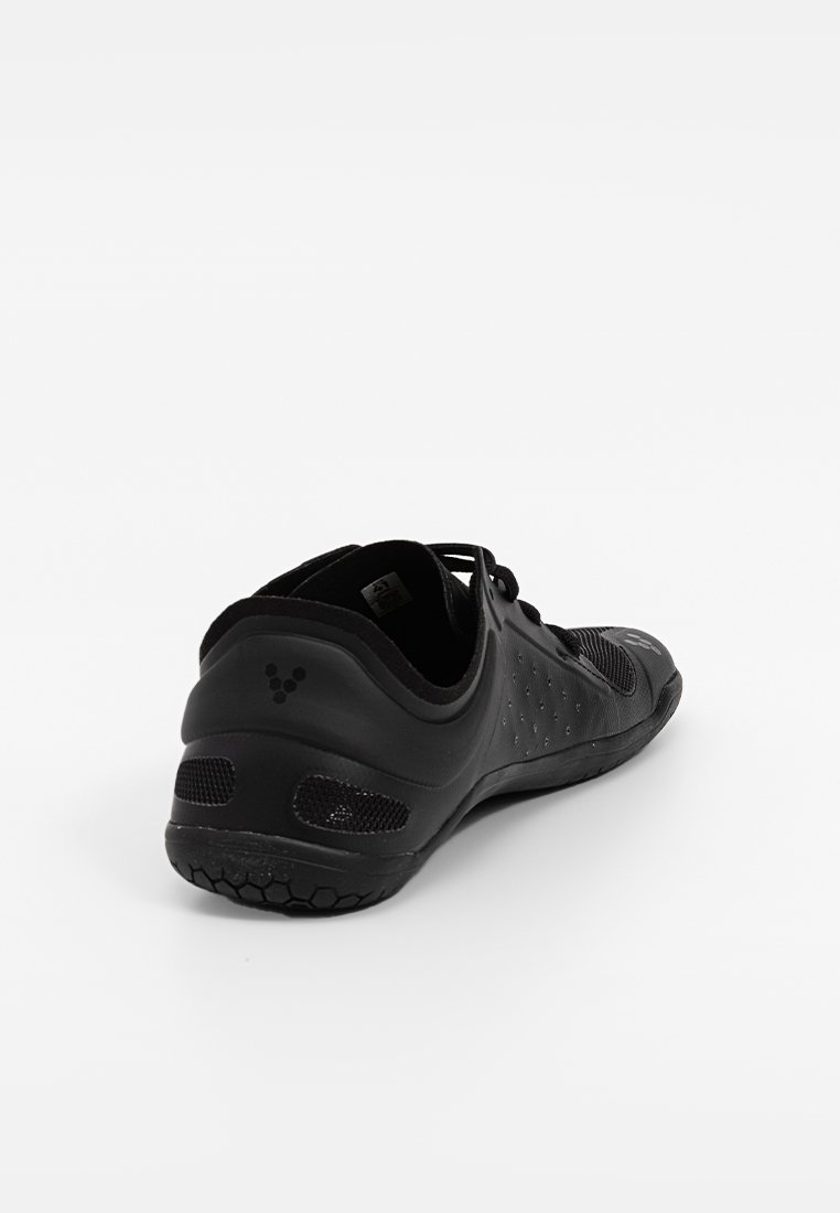 Zwarte sportieve schoen met een bovenwerk van mesh, gestructureerde details, vetersysteem en een flexibele rubberen zool met een hexagonaal patroon.
