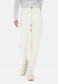 Weiße, hoch taillierte Jeans mit geradem Bein und fünf Taschen. Getragen mit einem gestreiften Langarmoberteil und hellen Sneakern.