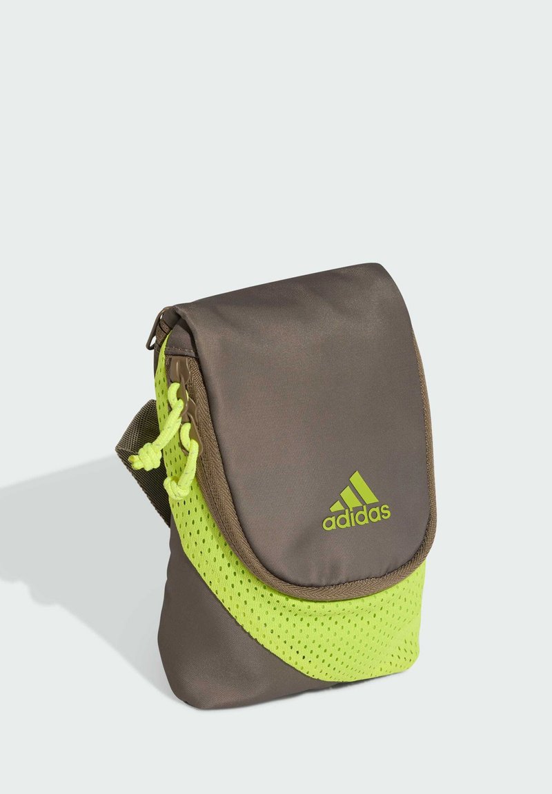 Kleine braune und neongrüne Adidas Schultertasche mit Klappverschluss und Logo vorne, mit Mesh- und Kordeldetails.