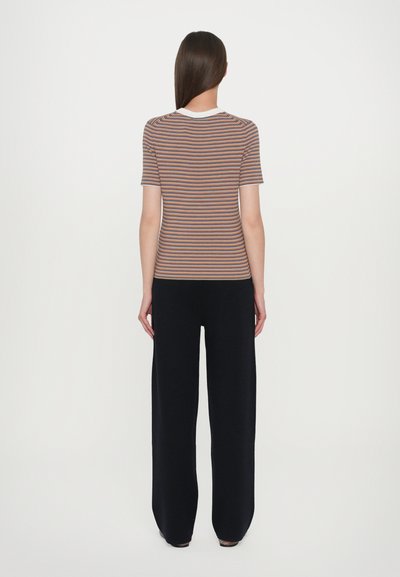 Gestreepte shirt in bruin, oranje en wit met een ronde halslijn, gecombineerd met brede zwarte broeken. Zachte textuur, casual pasvorm. Minimalistisch ontwerp.