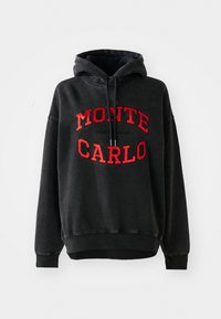 Mustmustaga mustsweater musta punase "MONTE CARLO" kirja ja nööpidega, millel on mugav lõige ning soonikkoes paisutajate ja alläär.