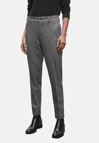 Pantalons à carreaux gris avec une coupe ajustée, un pli avant unique et deux poches avant, portés avec des bottines noires. Texture lisse.