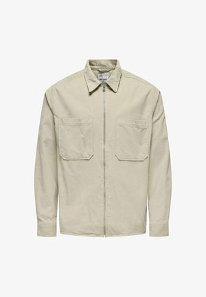 Svijetlo bež jakna na zatvaranje sa patentnim zatvaračem, izrađena od žoržeta. Ima dva prednja džepa na prsima i klasičan ovratnik sa rebrastim manžetama.