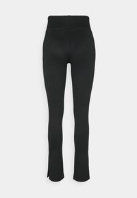 Leggings pretos com ribas e uma cintura alta, apresentando um ajuste justo e aberturas laterais nos tornozelos para maior flexibilidade e facilidade de movimento.