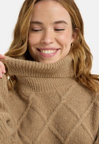 Beige gestrickter Rollkragenpullover mit strukturierten Rautenmustern, geripptem Kragen und weichem, flauschigem Material. Bietet eine lockere Passform und ein gemütliches Design.