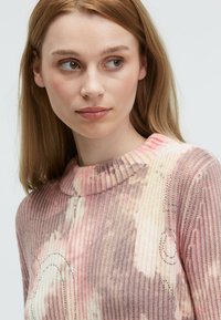 Rippstrickpullover in Rosa- und Cremetönen, mit einem kurzen Kragen, abstrakten Mustern und dezenten Verzierungen.